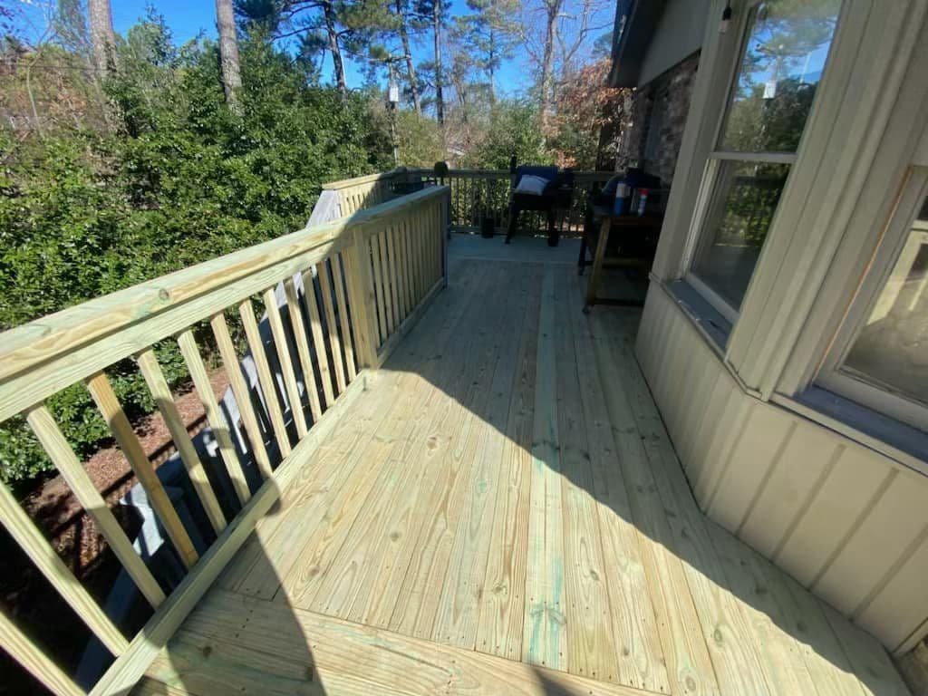 Newly constructed wooden deck with railings in a wooded backyard setting.