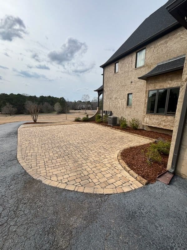 Paved driveway with landscaping beside a modern house on a cloudy day.