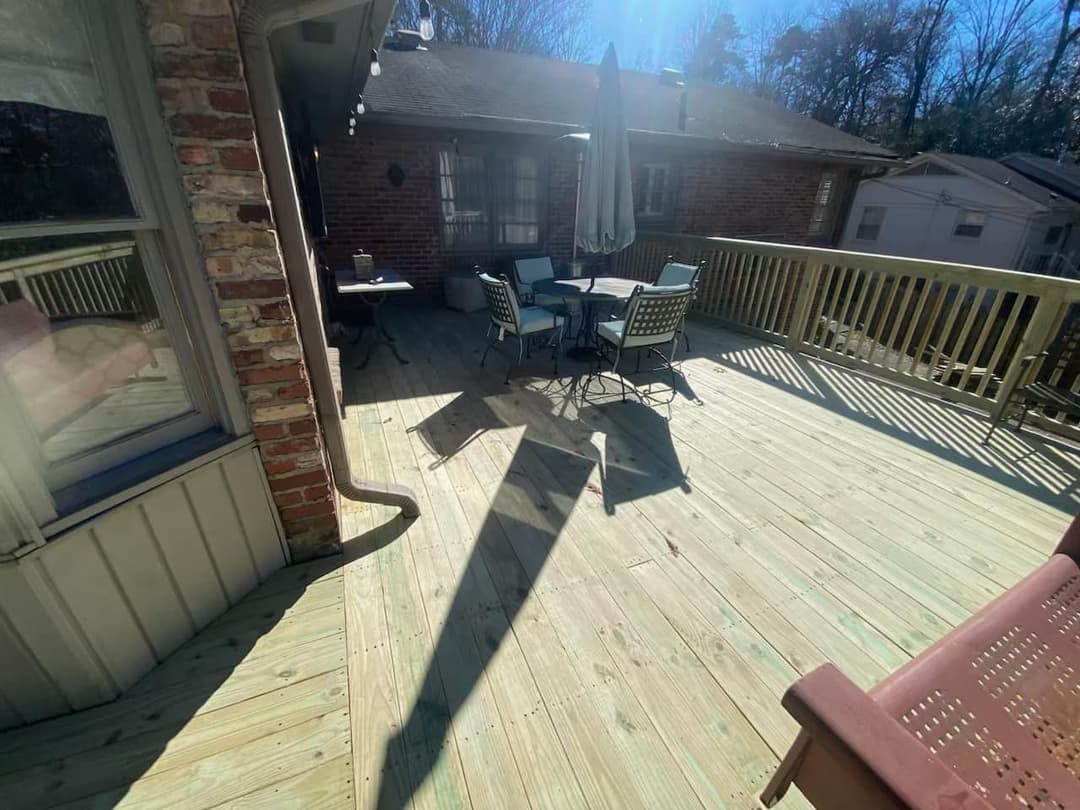 Sunny wooden deck with outdoor seating and an umbrella on a residential home.