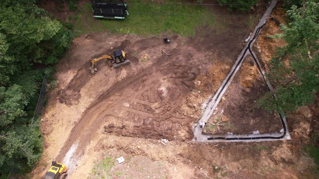 Aerial view of a construction site with heavy machinery and earth moved for foundation work.