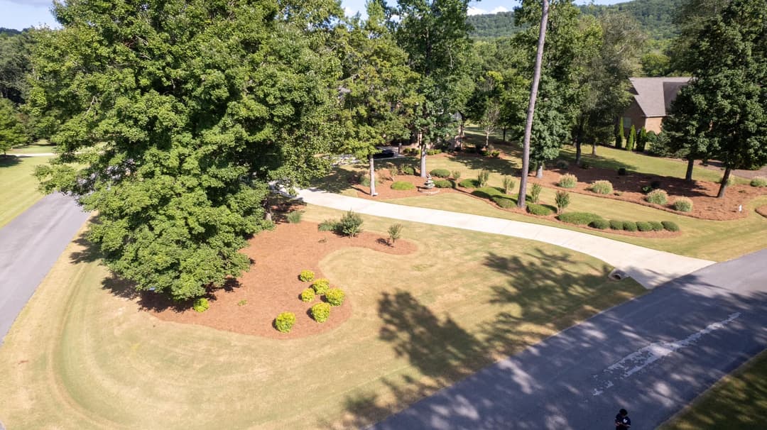 Aerial view of a landscaped yard featuring trees, shrubs, and winding pathways.