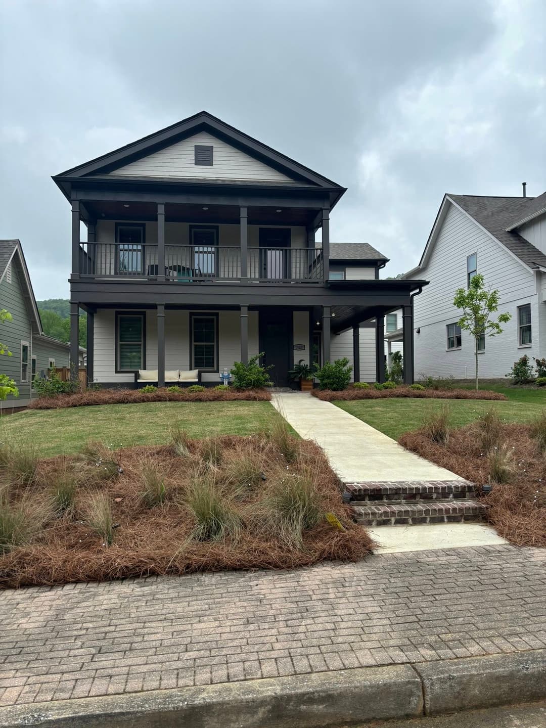 Two-story modern home with porch, landscaped yard, and brick walkway.