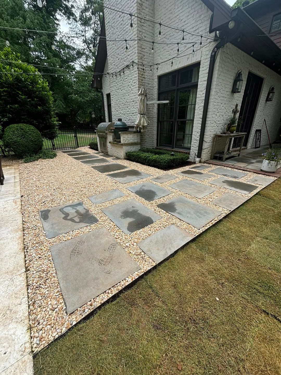 Outdoor patio featuring stone pavers and decorative gravel pathway surrounded by greenery.