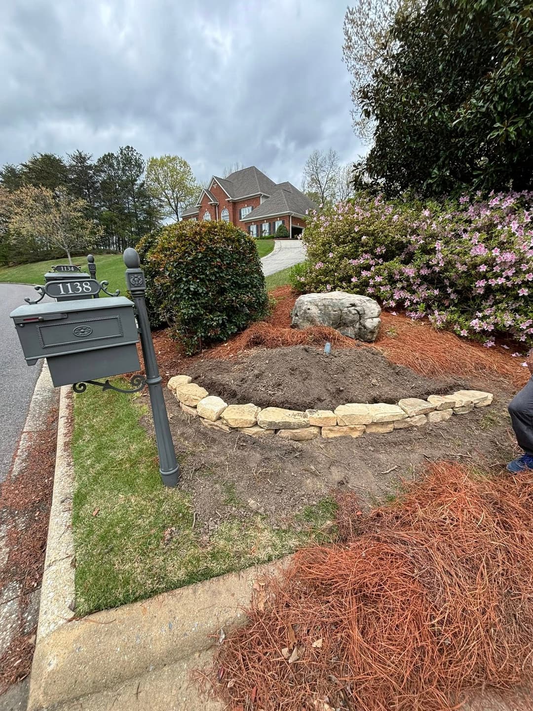Mailbox at 1138 with landscaped garden bed and stone border in residential area.