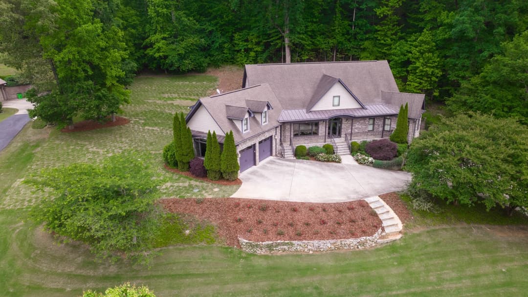 Aerial view of a beautiful modern home surrounded by lush greenery and landscaped yard.