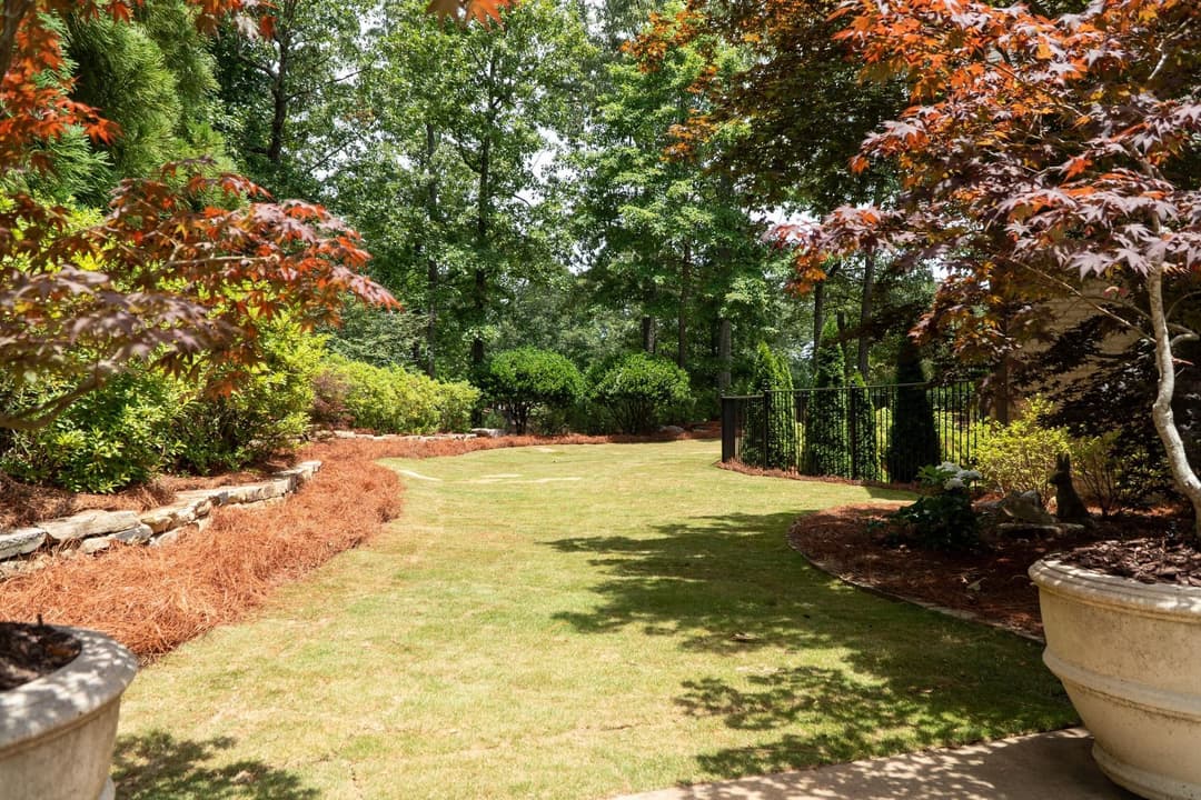 Lush green garden pathway surrounded by vibrant trees and manicured shrubs in a serene setting.