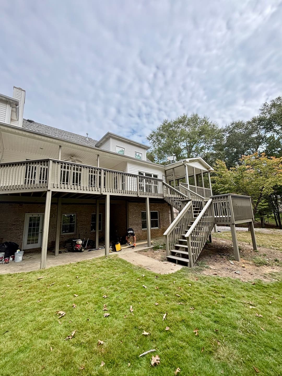 Home exterior featuring a wooden deck with stairs and a screened porch overlooking a yard.