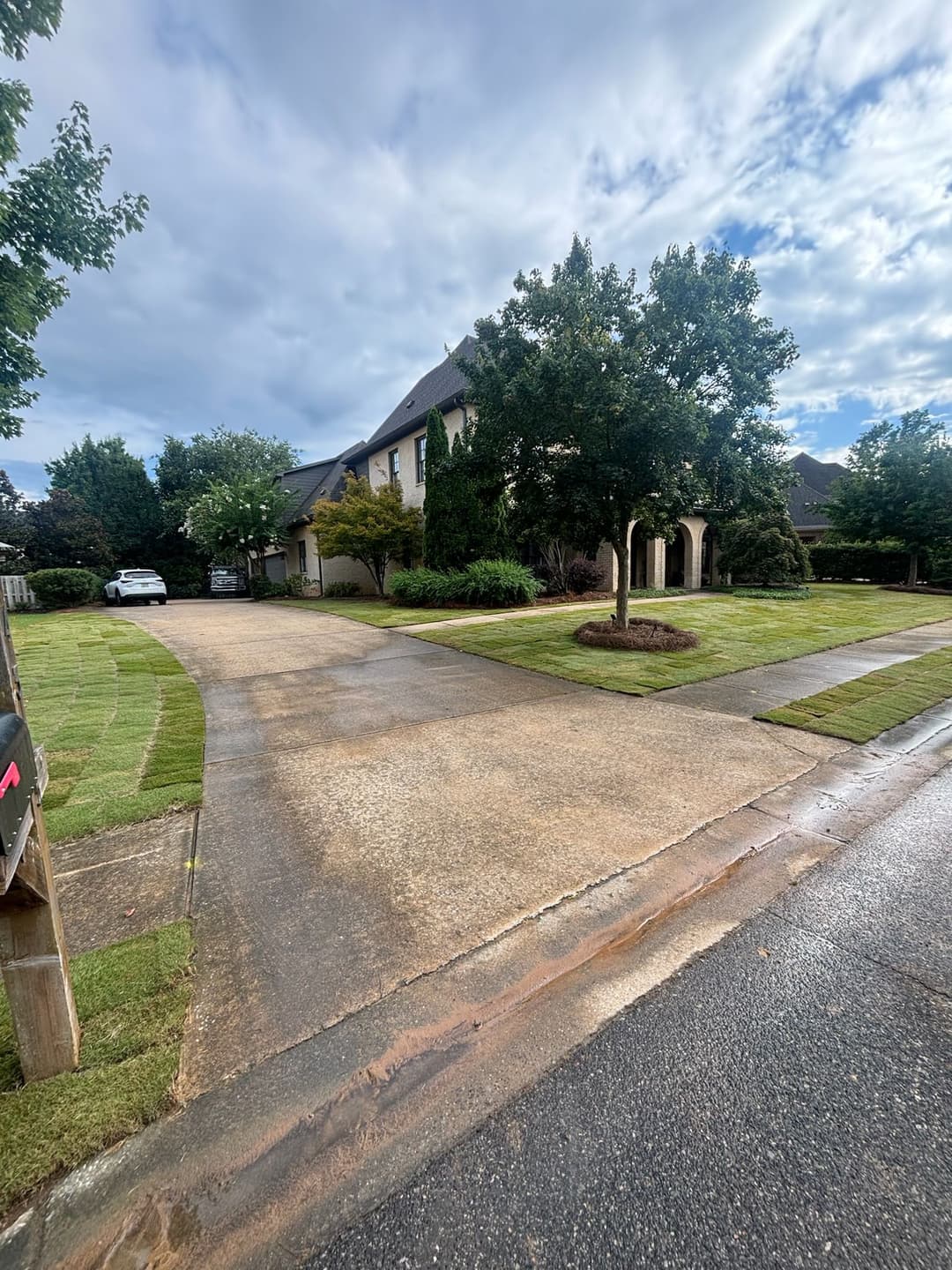 Elegant home with landscaped yard, driveway, and cloudy sky in the background.