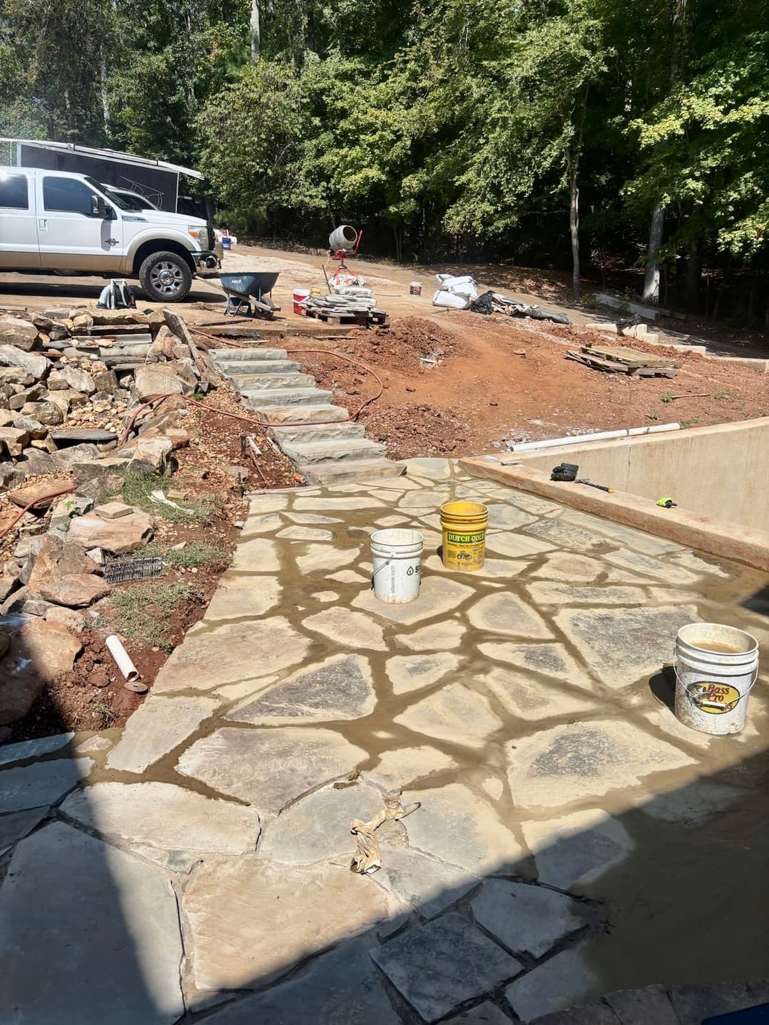 Stone pathway under construction with landscaping and equipment in background.