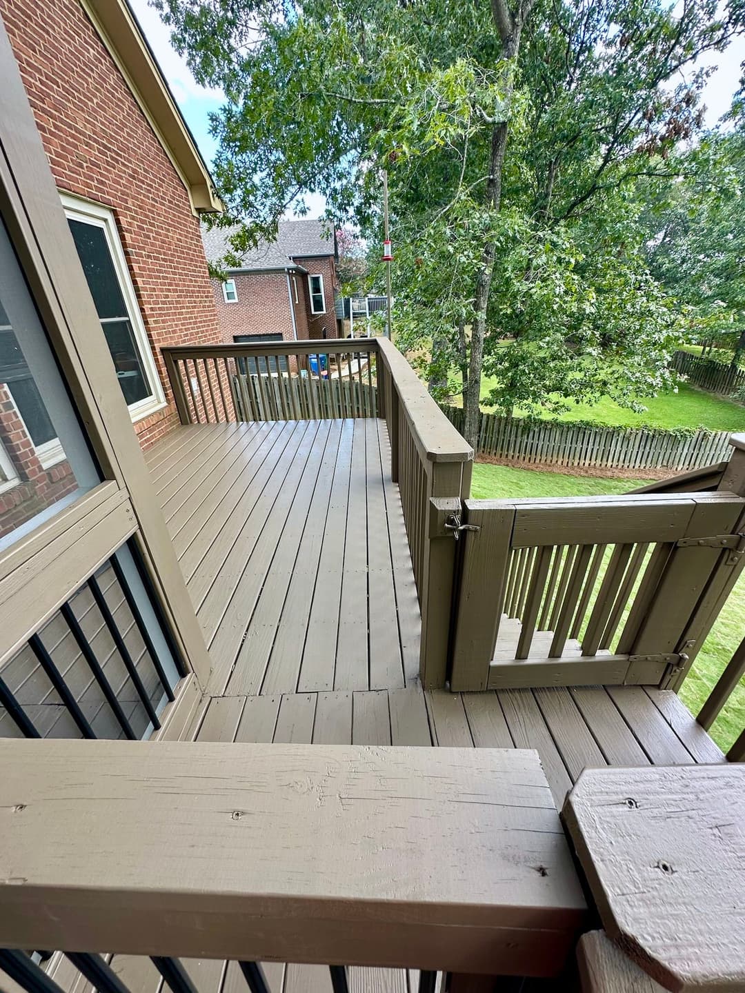 Spacious wooden deck with railing and trees in the background. Perfect for outdoor gatherings.