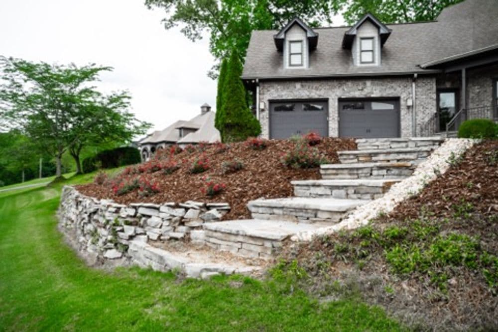 Beautiful stone landscaping leads to a modern brick home with a well-maintained garden.