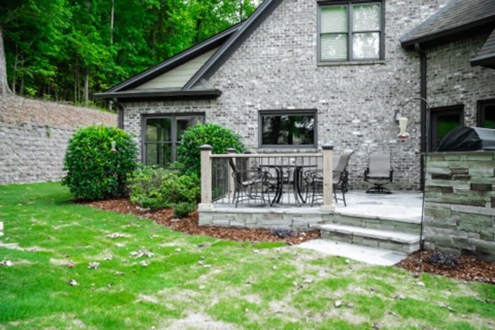 Modern brick home exterior with patio, greenery, and landscaped yard. Perfect for outdoor living.