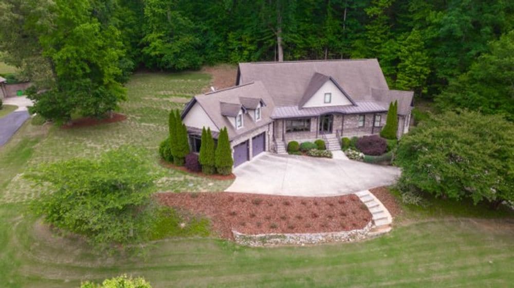 Aerial view of a modern home surrounded by lush greenery and landscaped gardens.