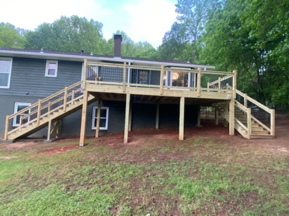 Newly constructed wooden deck with stairs at a residential home surrounded by greenery.
