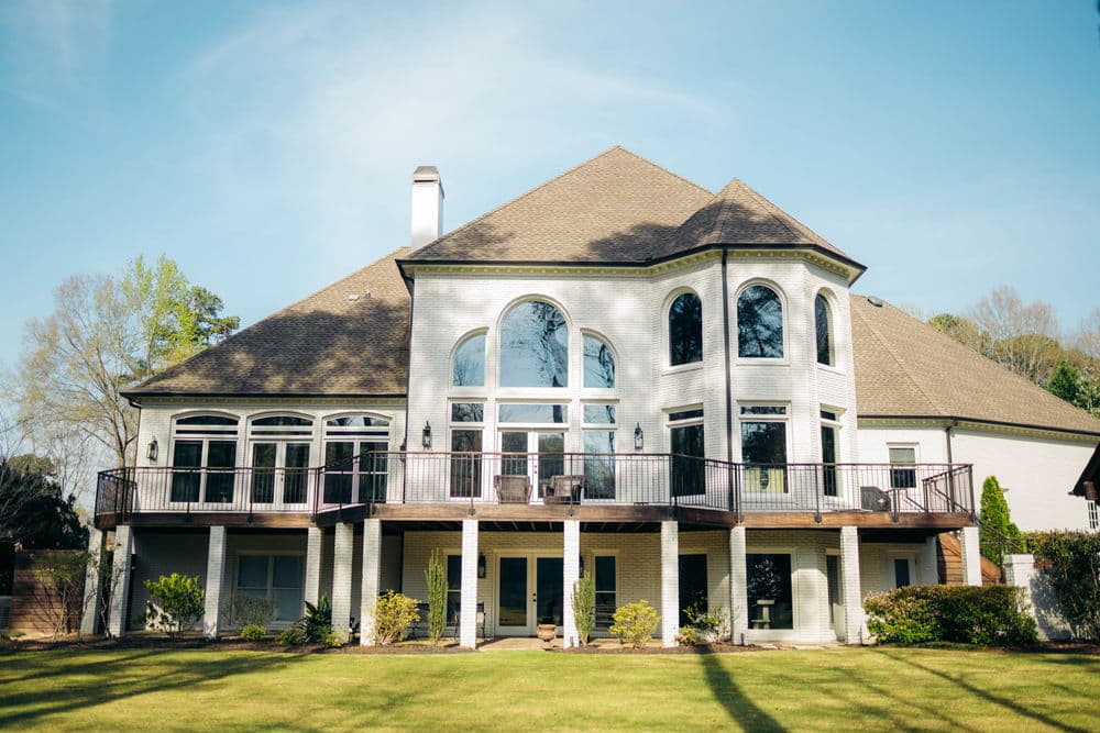 Modern two-story home with large windows and backyard patio surrounded by greenery.